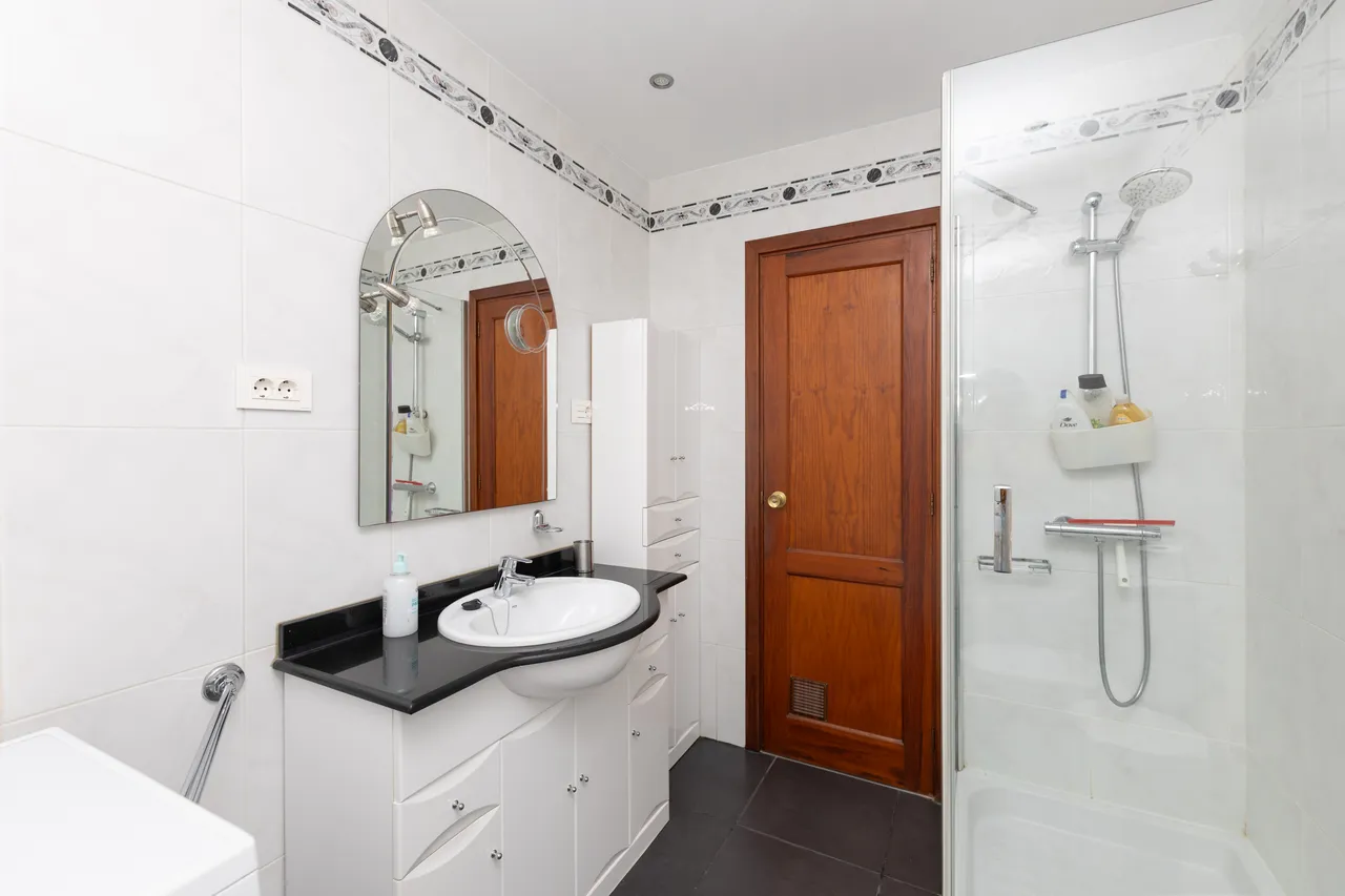 Badezimmer mit Waschbecken, Spiegel und Dusche