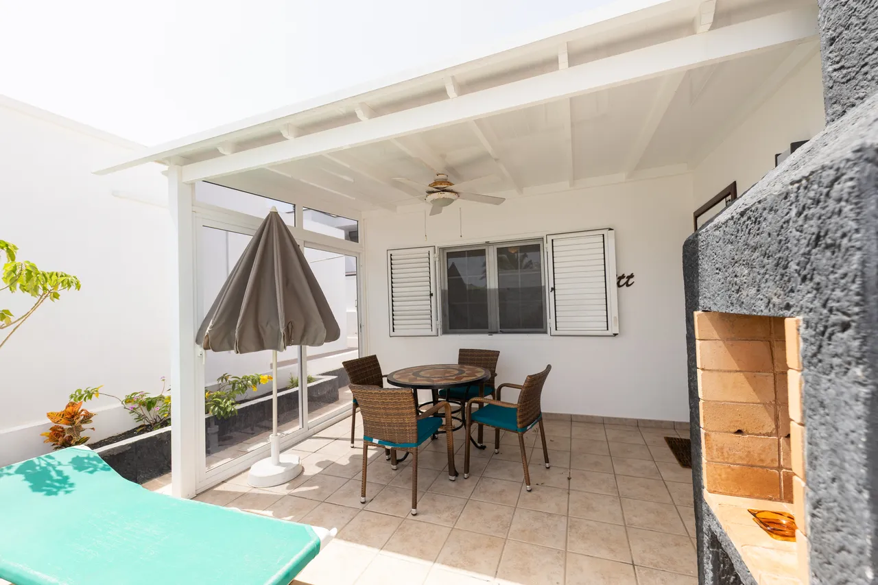 Überdachter Terrassen-Essbereich mit Sonnenschirm und Grill